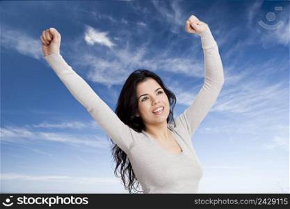 Happy young woman with arms up agains a blue sky