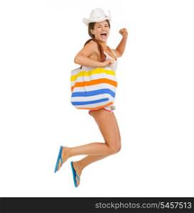 Happy young woman with beach bag jumping
