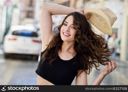 Happy young woman with blue eyes smiling in urban background. Girl wearing summer clothes and sun hat.