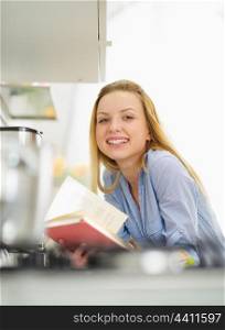 Happy young woman with book in kitchen