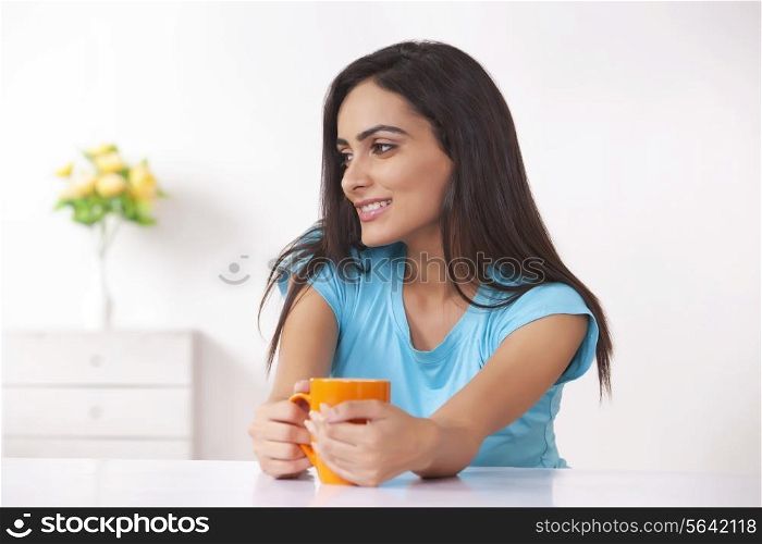 Happy young woman with coffee cup at home