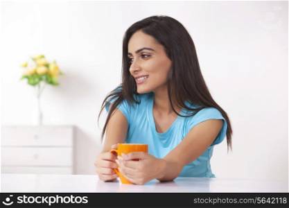 Happy young woman with coffee cup at home