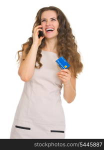 Happy young woman with credit card talking mobile phone