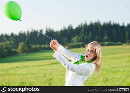 Happy young woman with green balloon in sunny meadows nature