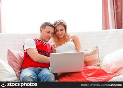 Happy young woman with husband working on laptop