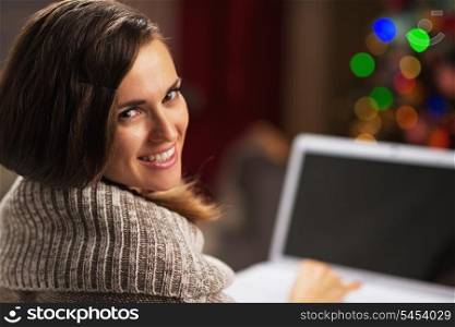 Happy young woman with laptop in front of christmas tree