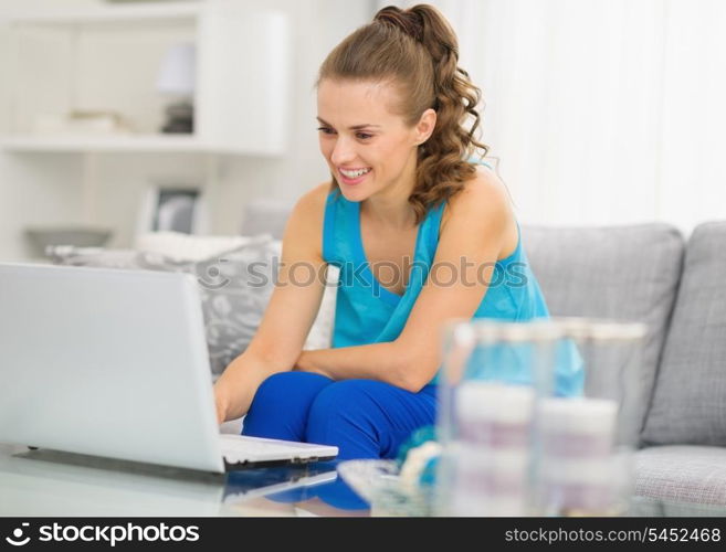 Happy young woman with laptop in living room