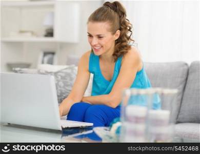 Happy young woman with laptop in living room