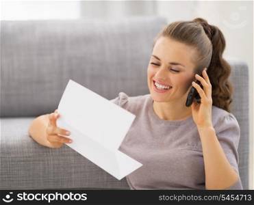 Happy young woman with letter talking cell phone