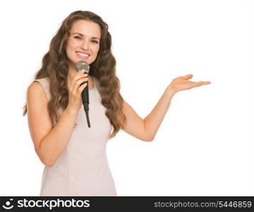 Happy young woman with microphone pointing on copy space