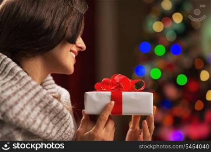 Happy young woman with present box in front of christmas lights