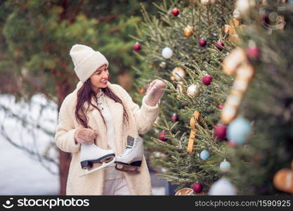 Happy young woman with skates ready to skate on ice rink. Smiling young girl skating on ice rink outdoors