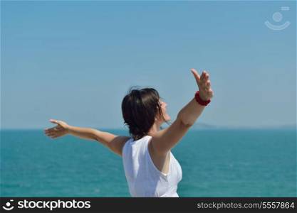 Happy young woman with spreading arms, blue sky with clouds in background - copyspace