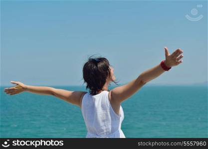 Happy young woman with spreading arms, blue sky with clouds in background - copyspace