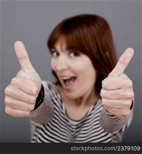 Happy young woman with thumb up over a grey background