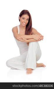 Happy young woman with white comfortable clothing sitting on the floor isolated