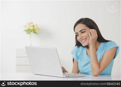 Happy young woman working on laptop at home