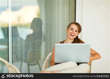 Happy young woman working on laptop on terrace