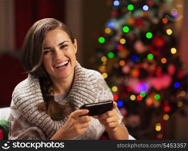 Happy young woman writing sms near christmas tree