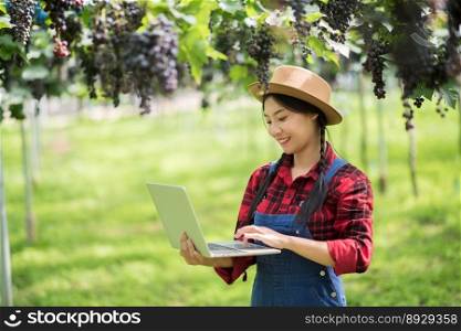 Happy young women gardener holding branches of ripe blue grape
