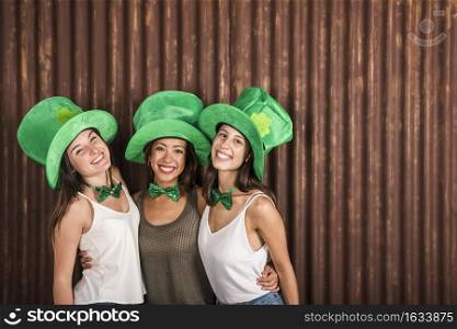 happy young women saint patricks hats embracing near wall