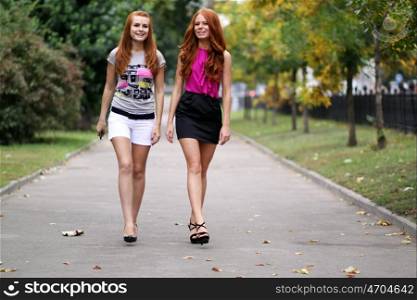 happy young women walking in summer park