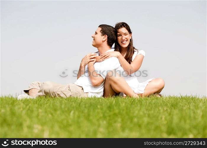Happy young women with arms around her husband in a green field