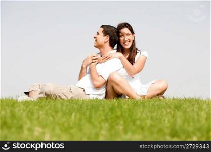 Happy young women with arms around her husband in a green field