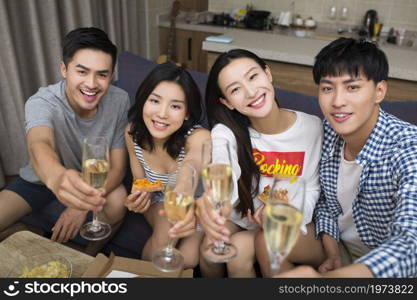 Happy youngsters drinking champagne in the living room