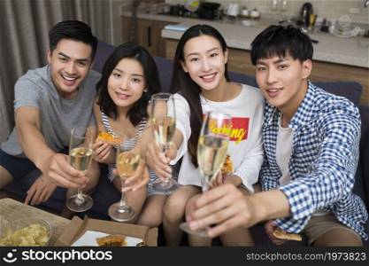 Happy youngsters drinking champagne in the living room