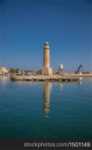 harbor and lighthouse of the city of rethymno in in crete greece , with boats, reflexions on the waves of the sea and clouds. harbor and lighthouse of the city of rethymno in in crete greece