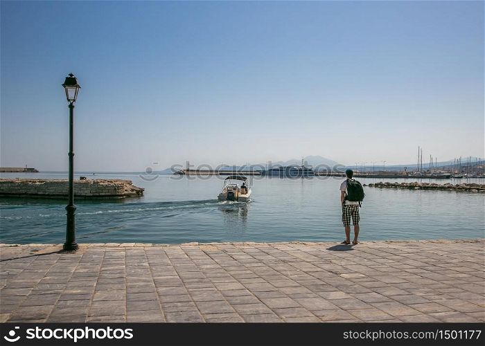 harbor and lighthouse of the city of rethymno in in crete greece , with boats, reflexions on the waves of the sea and clouds. harbor and lighthouse of the city of rethymno in in crete greece