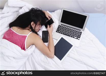 Hard work or hard play in technology. Tired young woman sleeping whille using technology devices.