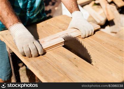 Hard working woodworker cutting wooden plank, focus on saw. Hard work on the sawmill