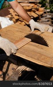 Hard working woodworker cutting wooden plank, focus on saw. Hard work on the sawmill