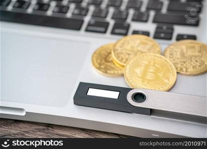 Hardware cryptocurrency wallet with golden Bitcoin (BTC) on computer. Safe storage for crypto.