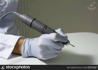 Hardware manicure electric drill in woman`s hands. Close up photo