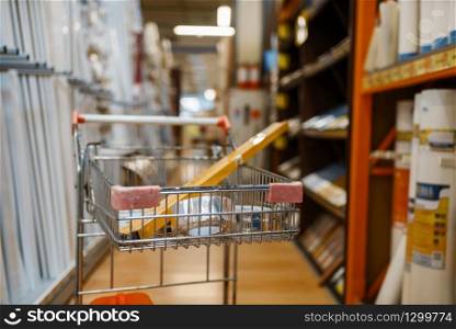 Hardware store assortment, cart with equipment, nobody. Building materials and tools choice in diy shop, rows of products on racks