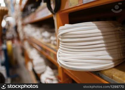 Hardware store assortment, shelf with wiring, nobody. Building materials and tools choice in diy shop, rows of products on racks