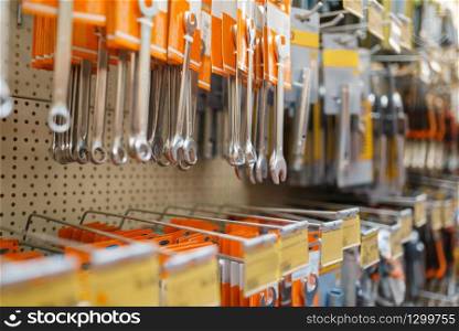 Hardware store assortment, shelf with wrenches, nobody. Building materials and tools choice in diy shop, rows of products on racks