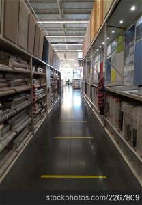 Hardware store with wallpaper rolls on both sides of the aisle. Store aisle with wallpaper rolls on both sides