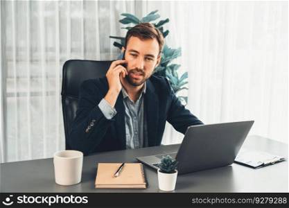 Hardworking and diligent businessman working on his laptop while talking to clients on his mobile phone, showcasing modern multitasking office worker lifestyle. Entity. Hardworking and diligent businessman working on his laptop and phone. Entity