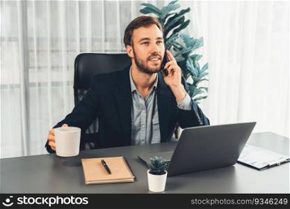 Hardworking and diligent businessman working on his laptop while talking to clients on his mobile phone, showcasing modern multitasking office worker lifestyle. Entity. Hardworking and diligent businessman working on his laptop and phone. Entity