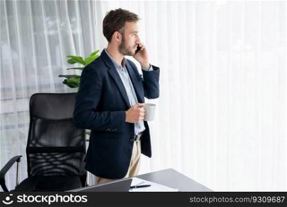 Hardworking businessman stand confidently in modern office making persuasive sales call to client. Office worker talking on the phone coordinate and manage business work with colleagues. Entity. Hardworking businessman stand in modern office talking on phone. Entity