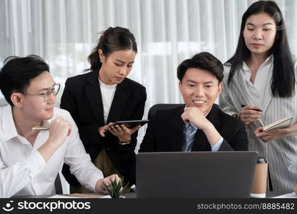 Harmony in office concept as business people analyzing dashboard paper together in workplace. Young colleagues give ideas at manager desk for discussion or strategy planning about project.. Engaging businesspeople working at desk together as concept of harmony in office