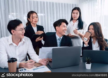 Harmony in office concept as business people analyzing dashboard paper together in workplace. Young colleagues give ideas at manager desk for discussion or strategy planning about project.. Engaging businesspeople working at desk together as concept of harmony in office