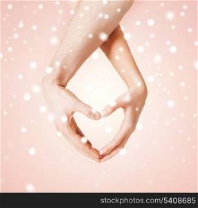 harmony, love, family and charity concept - woman and man hands showing heart shape