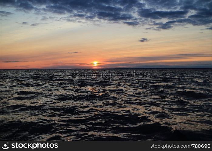 harsh sea in the evening at sunset, dramatic seascape setting sun red horizon