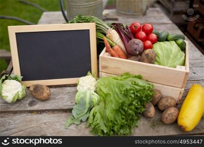 harvest, food and agriculture concept - close up of vegetables with chalkboard on farm. close up of vegetables with chalkboard on farm
