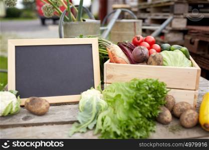 harvest, food and agriculture concept - close up of vegetables with chalkboard on farm. close up of vegetables with chalkboard on farm